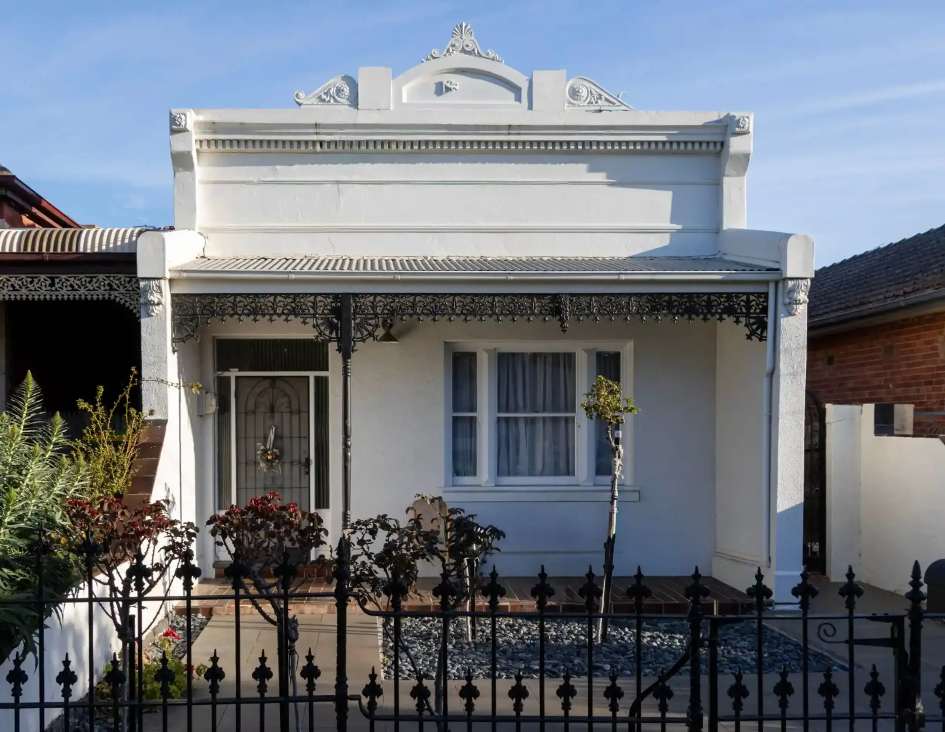 Victorian house painted white with black lacework and traditional ironwork fence